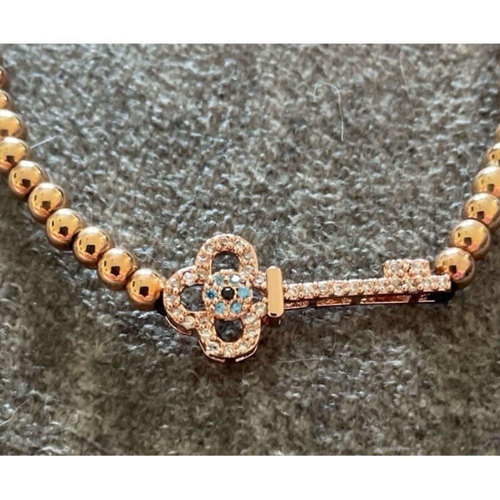 Gold beaded‎ bracelet with a crystal key charm.